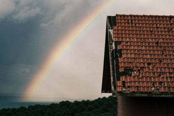 damaged roof outside with a rainbow in the background